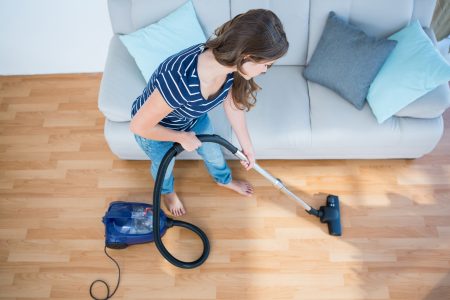 Woman using vacuum cleaner on wooden floor